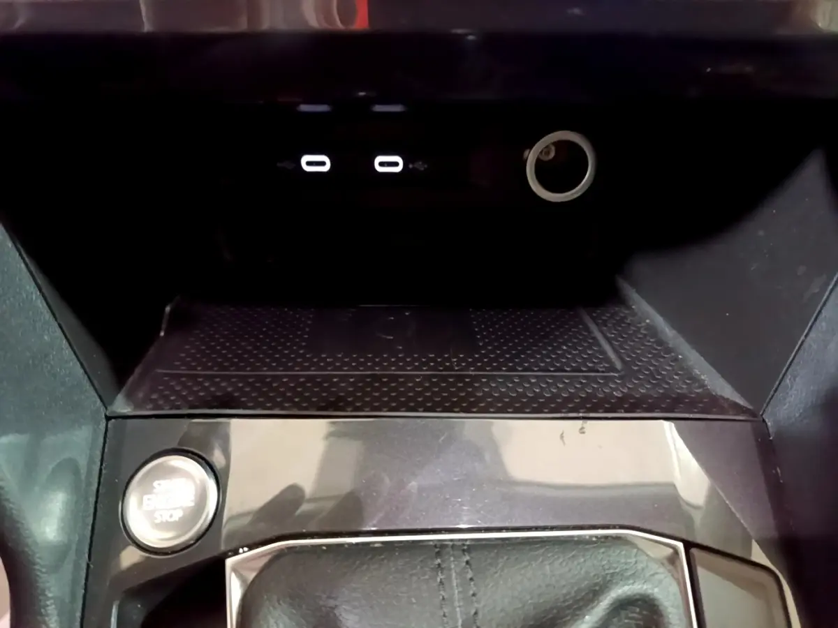 Gros plan sur la console centrale du Volkswagen Tiguan gris foncé, avec bouton démarrage et ports USB visibles.