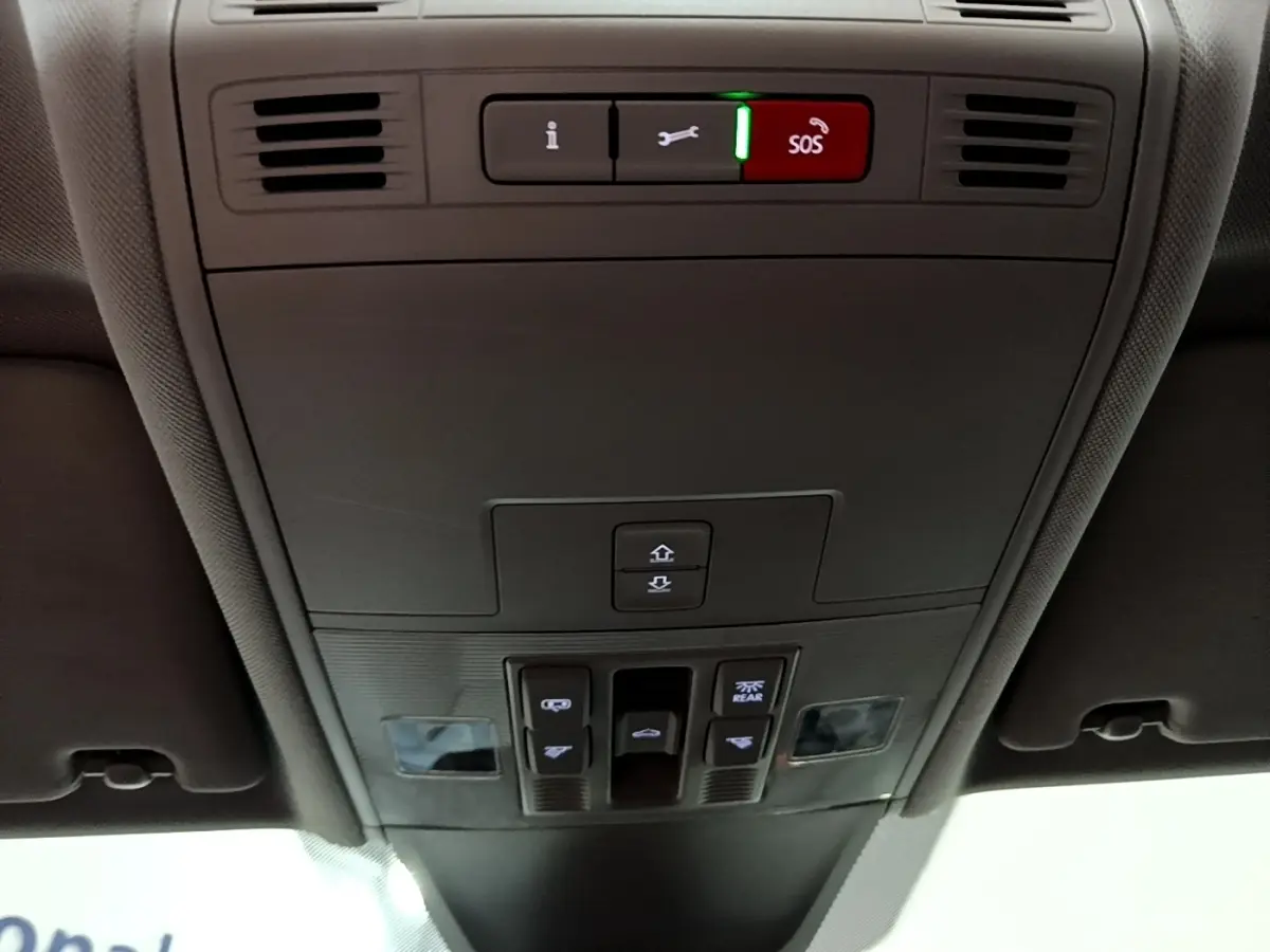 Vue en contre-plongée du panneau de commandes au plafond gris foncé du Volkswagen Tiguan 2021 avec bouton SOS rouge allumé.