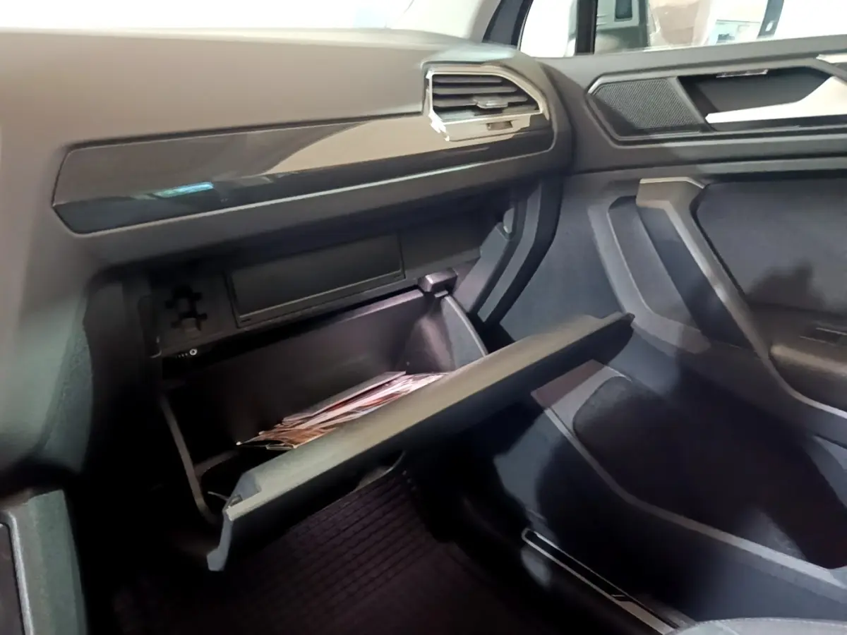 Intérieur du Volkswagen Tiguan 2021, vue côté passager sur la boîte à gants ouverte et tableau de bord gris foncé.