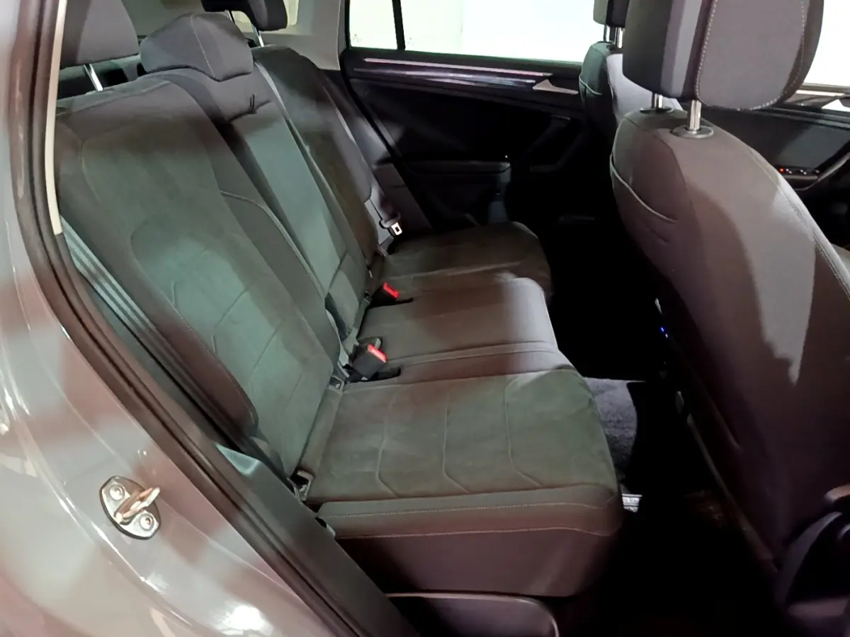 Vue intérieure côté gauche des sièges arrière gris foncé du Volkswagen Tiguan 2021 avec garniture tissu et ceintures visibles.