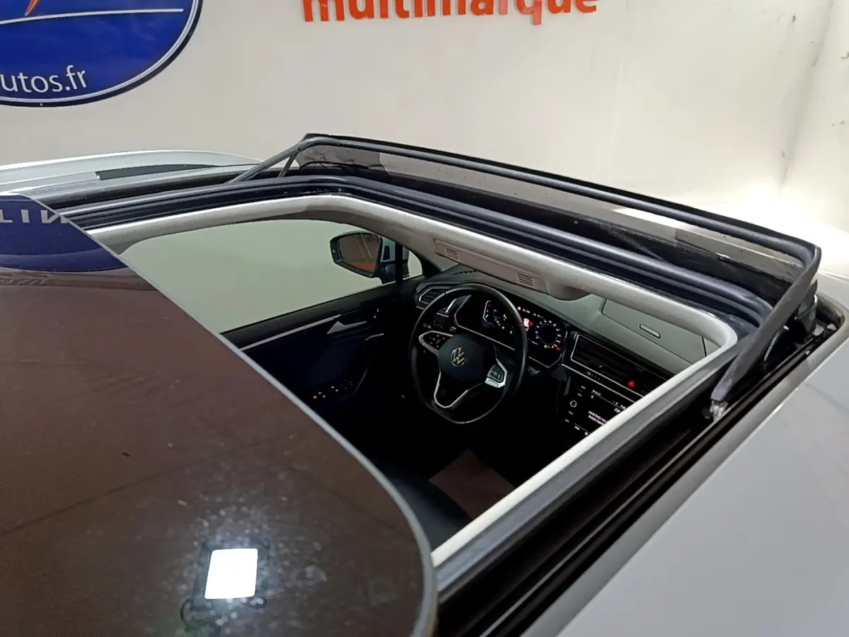 Vue plongeante sur l'intérieur noir et gris du Volkswagen Tiguan 2021 via son toit ouvrant panoramique ouvert.