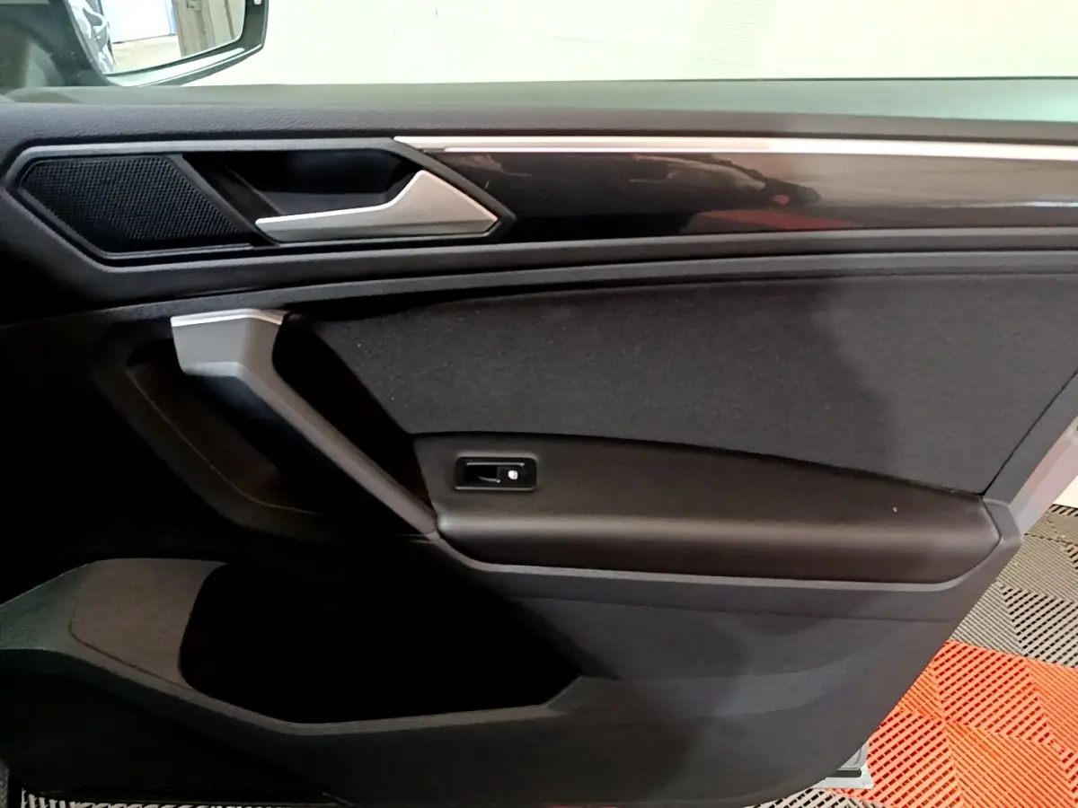 Vue rapprochée de la porte côté gauche du Volkswagen Tiguan 2021 gris foncé, avec poignée argentée et panneau noir.