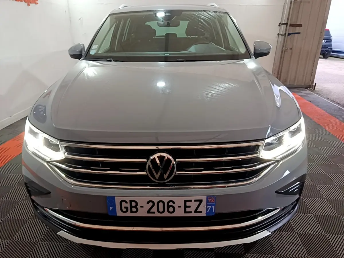 Vue avant d'un Volkswagen Tiguan gris foncé avec phares LED allumés dans un garage fermé.