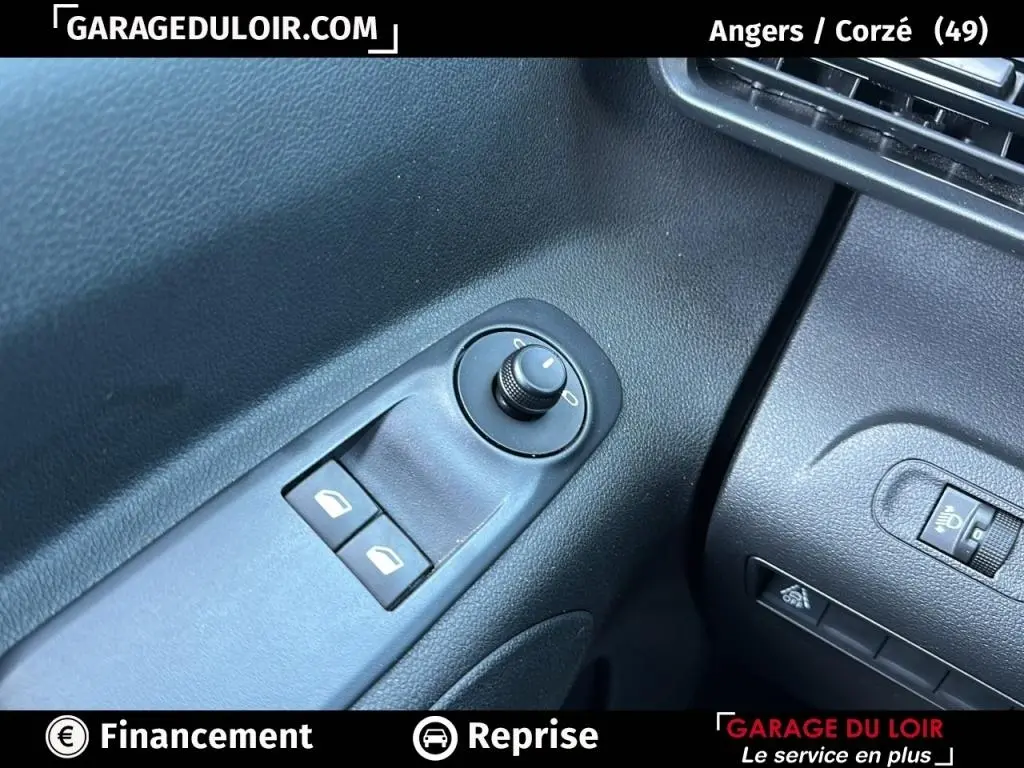 Détail des commandes de réglage des rétroviseurs et des vitres côté conducteur dans l’habitacle noir du Peugeot Rifter bleu 2024.