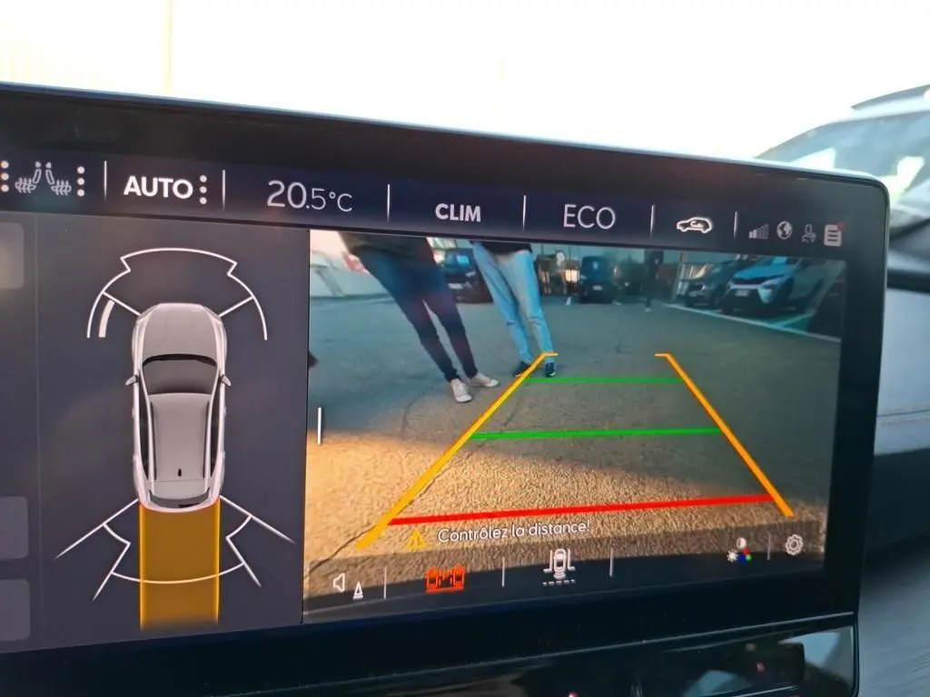 Vue de l'écran de caméra de recul du CUPRA Formentor gris foncé, avec guidage de trajectoire et personnes visibles derrière.