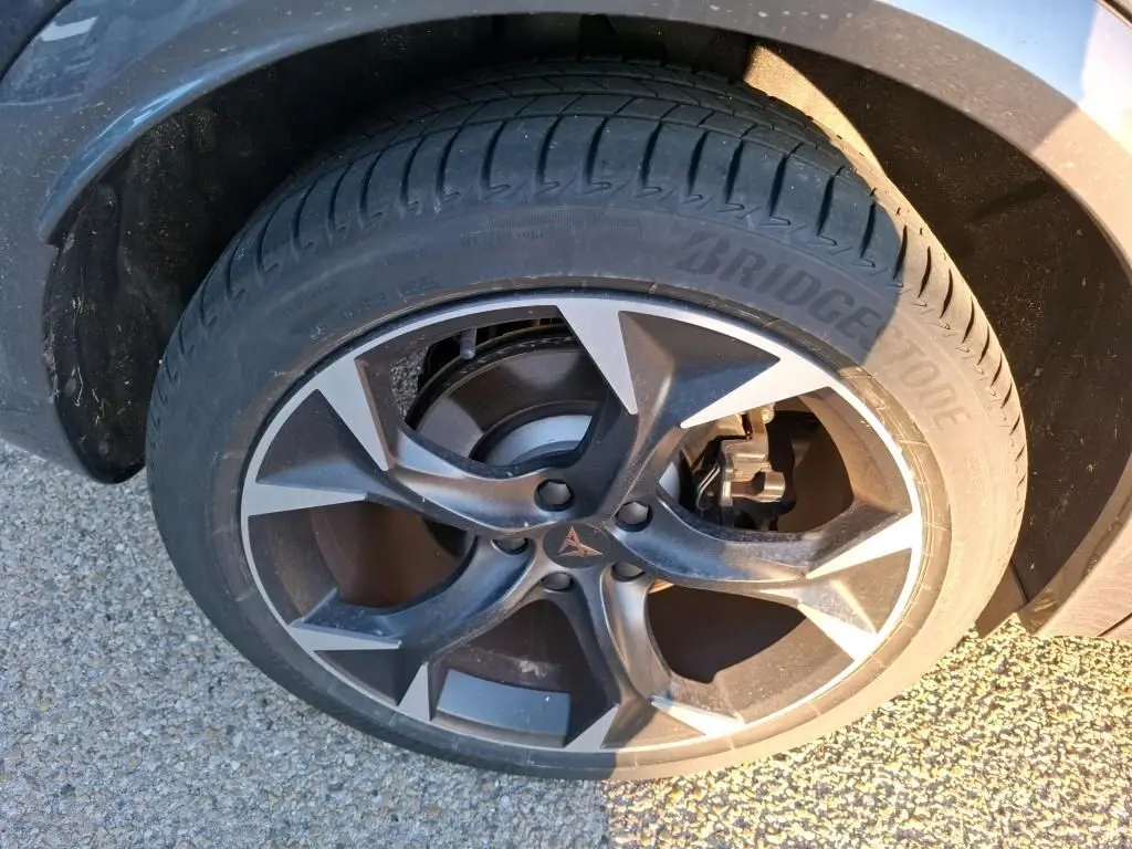 Gros plan sur la roue avant droite du CUPRA Formentor gris foncé, mettant en valeur la jante alliage et le pneu Bridgestone.