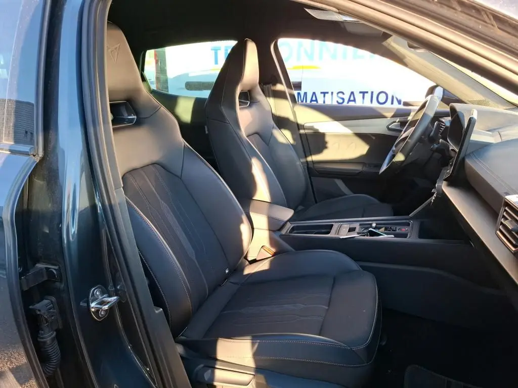 Vue intérieure côté conducteur du CUPRA Formentor gris foncé 2023, mettant en valeur les sièges sport en tissu noir avec surpiqûres contrastées.