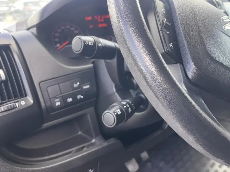 Vue rapprochée du volant multifonction et des commandes au volant du Citroën Jumper blanc, avec tableau de bord partiellement visible.