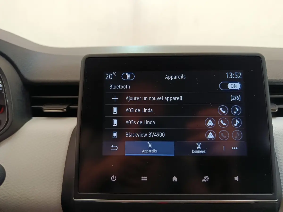 Écran tactile central de la Renault Clio blanc, affichant le menu Bluetooth avec plusieurs appareils connectés.