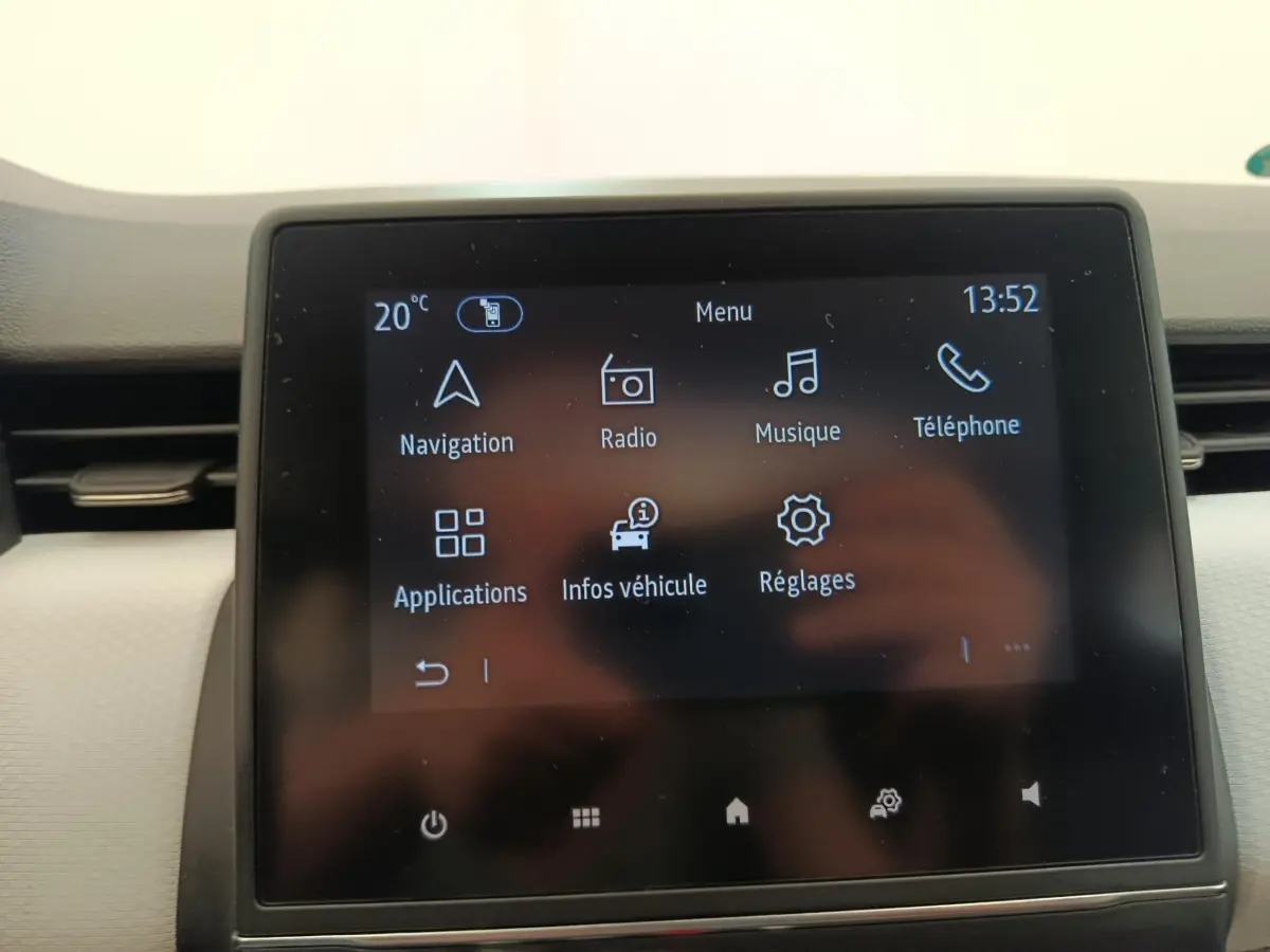 Écran tactile central de la Renault Clio blanc 2023 affichant le menu navigation, radio, musique et téléphone.