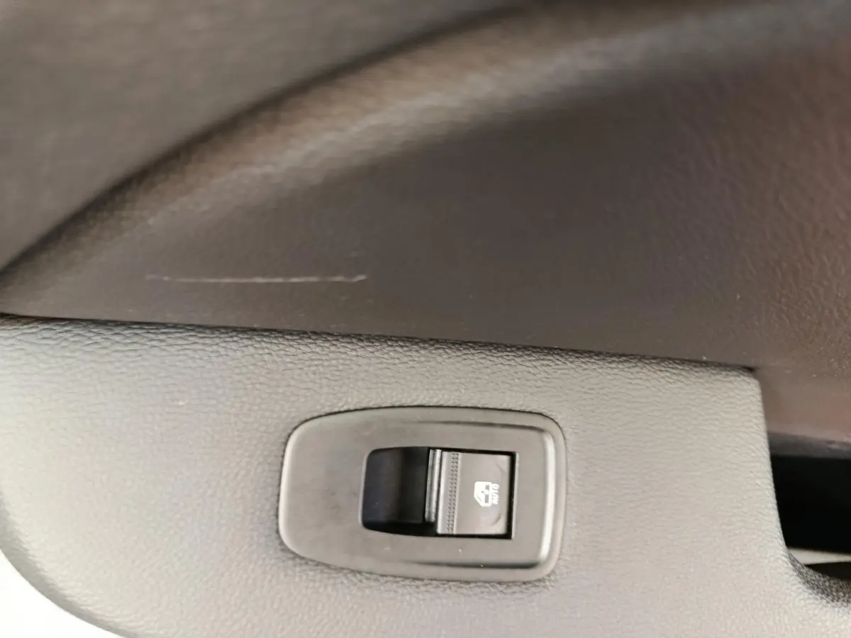 Gros plan sur l'interrupteur de verrouillage des vitres arrière dans une Renault Clio blanche Evolution TCe 100 GPL.