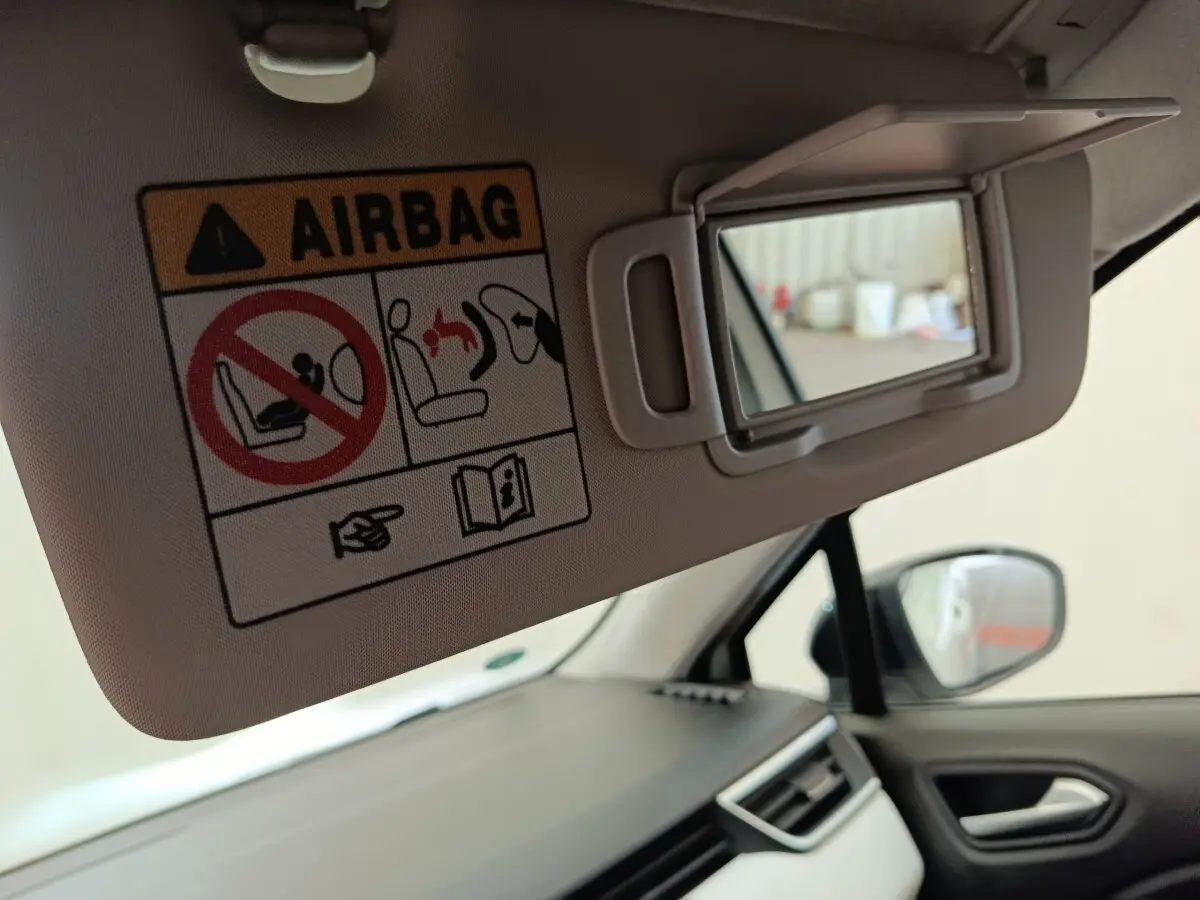 Vue intérieure côté passager avant de la Renault Clio blanche, avec pare-soleil déplié et miroir de courtoisie visible.