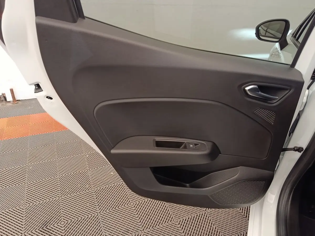 Vue intérieure de la porte avant droite noire d'une Renault Clio blanche 2023, avec poignée et commande de vitre électrique.