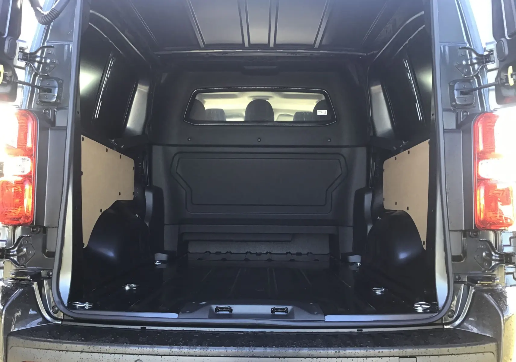 Vue arrière ouverte du Citroën Jumpy XL gris titane, montrant la cabine approfondie et l'espace de chargement vide.