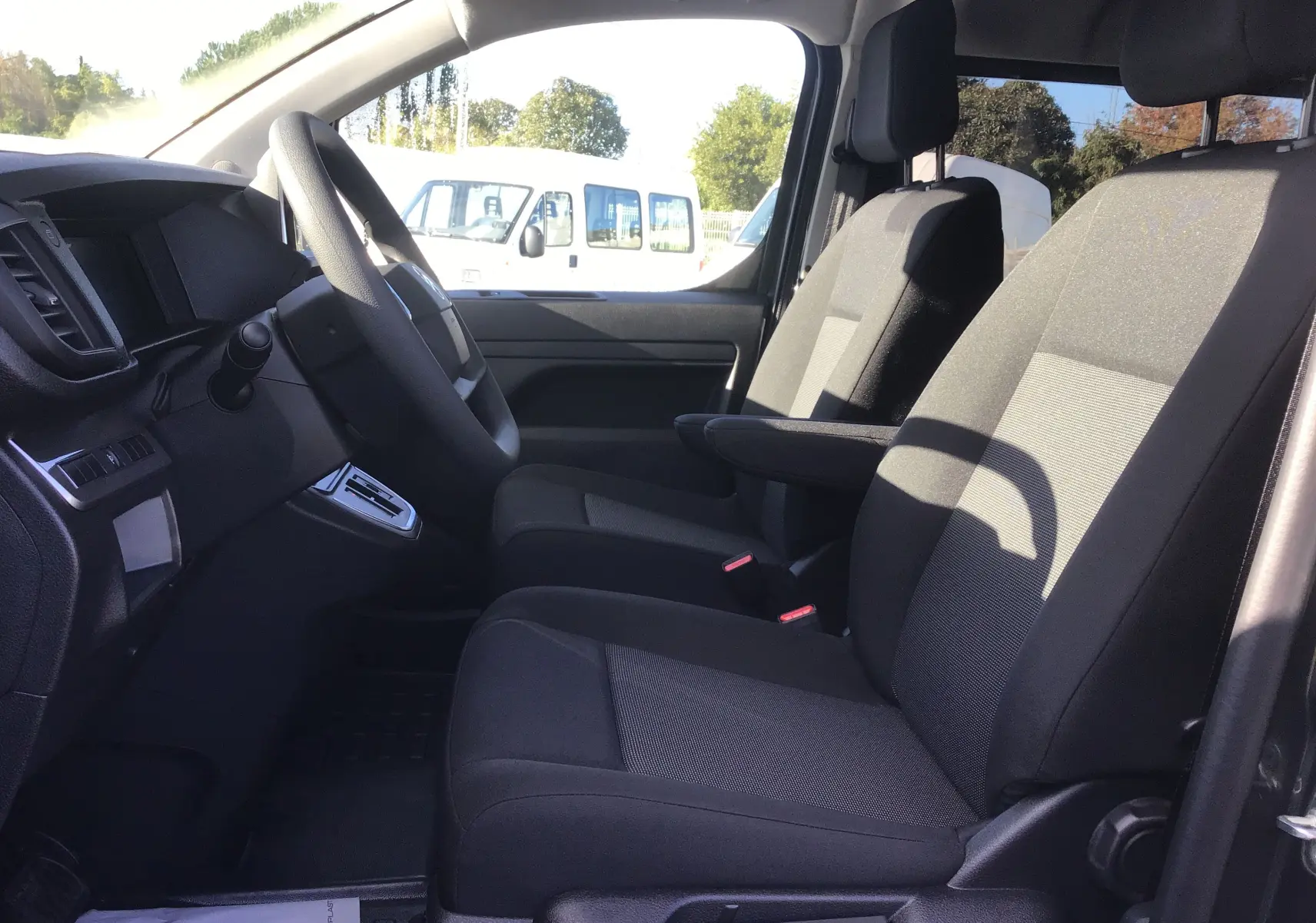 Vue intérieure côté conducteur du Citroën Jumpy gris titane, montrant les sièges avant et le volant.