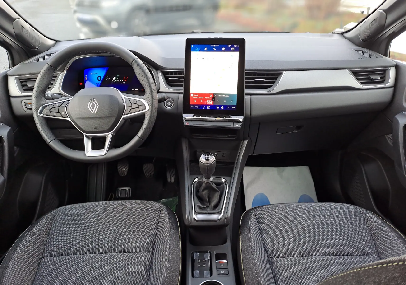 Vue intérieure frontale du tableau de bord noir du Renault Symbioz 2025 avec écran tactile vertical et boîte manuelle.