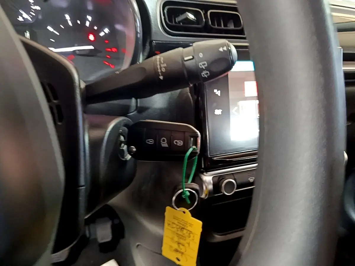 Vue rapprochée de l’intérieur de la Citroën C3 bleu, montrant le volant, le tableau de bord et la clé insérée dans le contact.