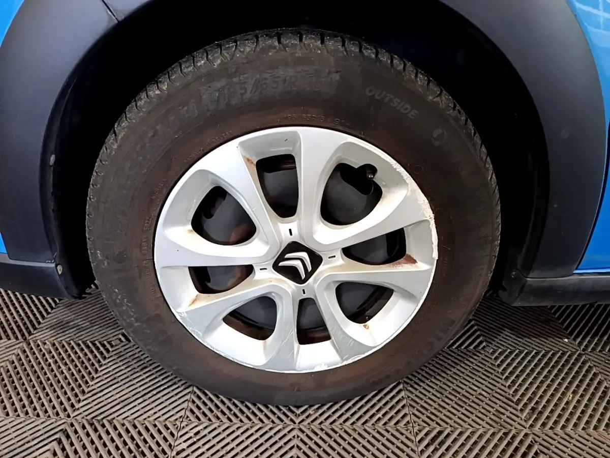 Gros plan sur la roue avant gauche d'une Citroën C3 bleu 2017 avec jante en alliage et logo Citroën central.