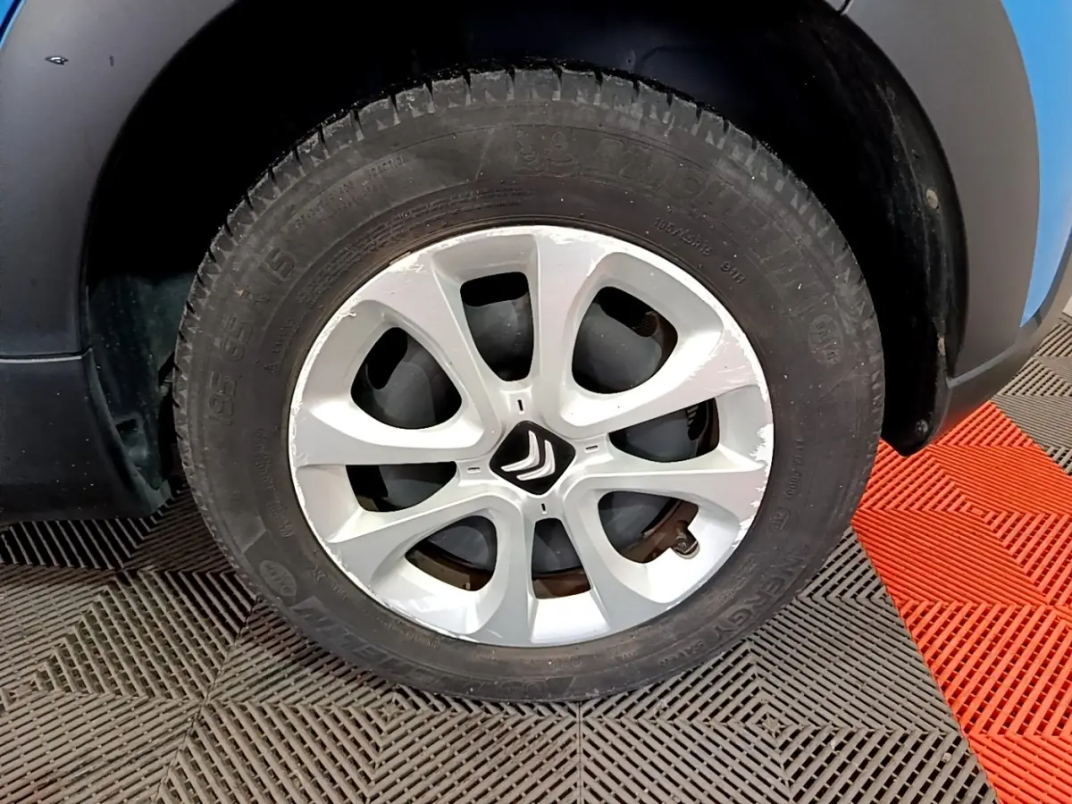 Gros plan sur la roue avant gauche d'une Citroën C3 bleue avec jante argentée et logo Citroën central.
