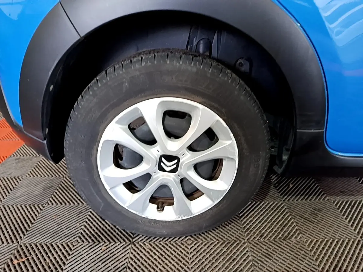 Gros plan sur la roue avant droite d'une Citroën C3 bleu 2017 avec jante argentée et logo Citroën central.