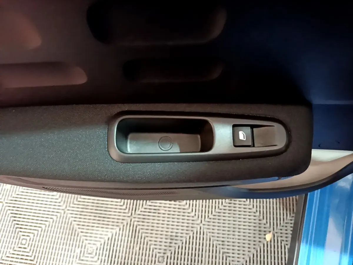 Poignée intérieure de porte côté gauche d'une Citroën C3 bleu 2017 avec bouton de commande de vitre électrique.