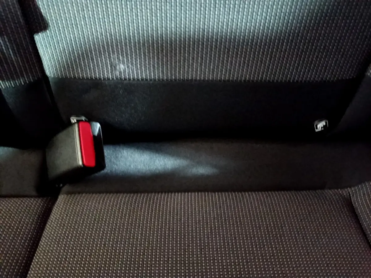Gros plan sur la ceinture de sécurité arrière rouge et noire d'une banquette tissu gris foncé d'une Citroën C3 2017.