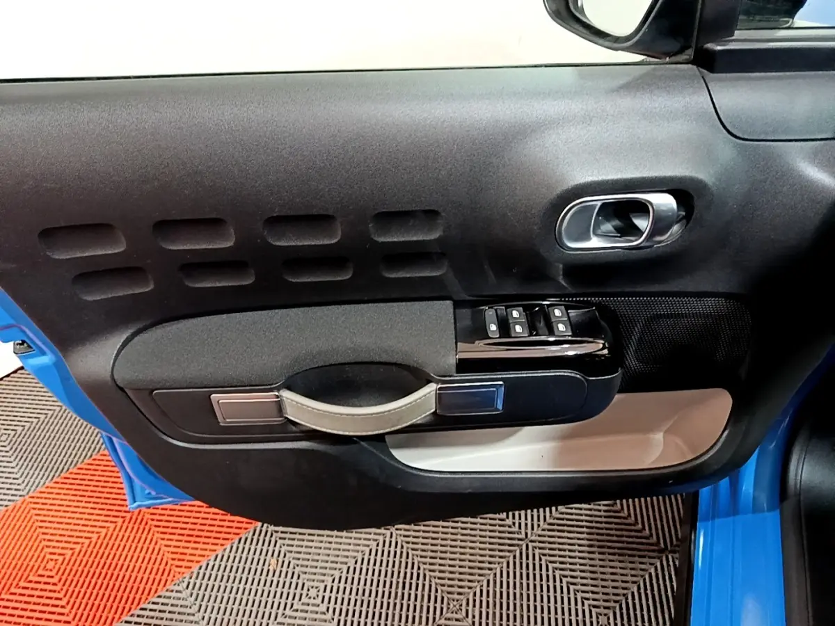 Gros plan sur la porte avant gauche bleu de la Citroën C3 2017, avec commandes de vitres et poignée intégrée.