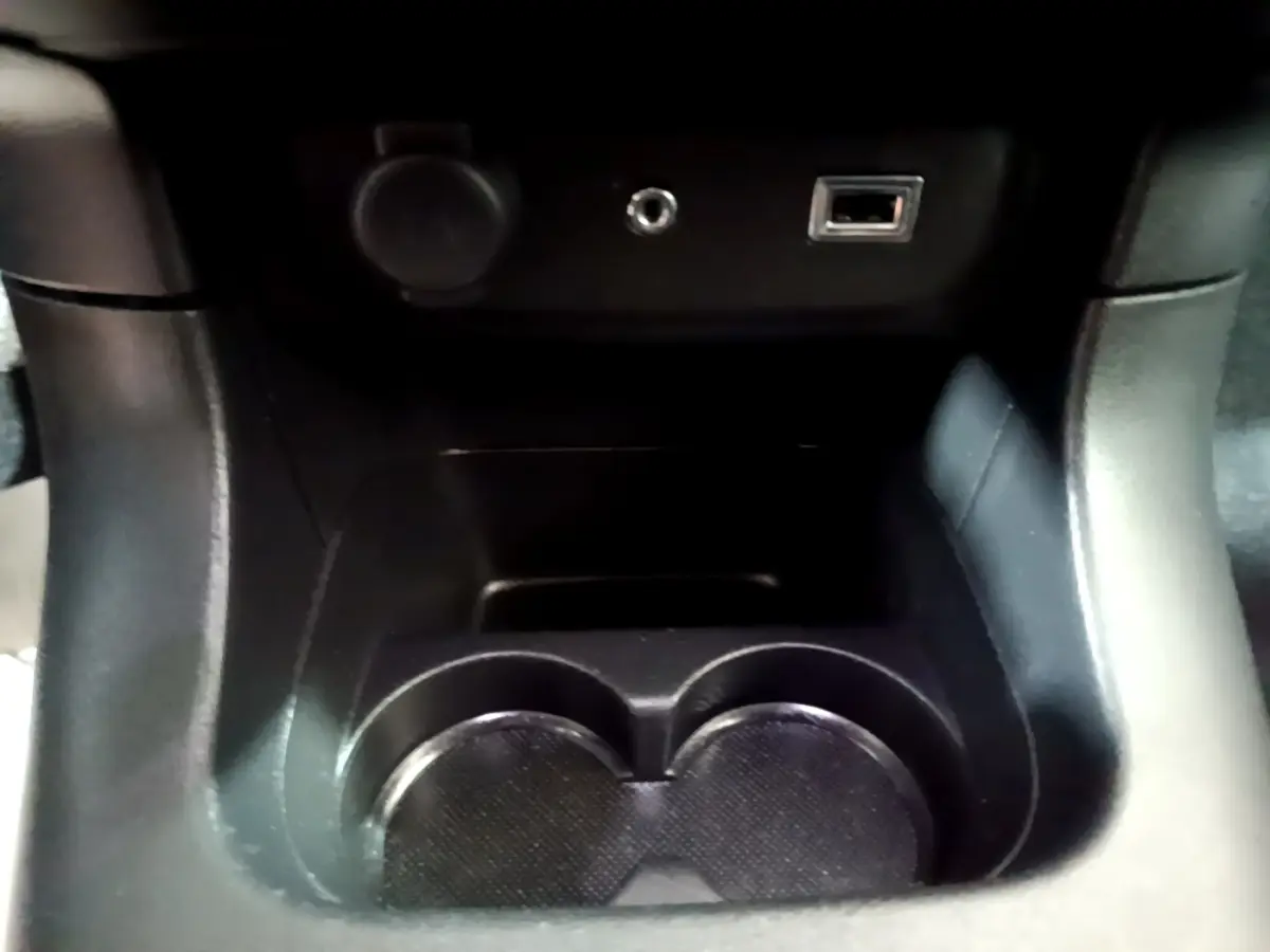 Gros plan sur la console centrale noire de la Citroën C3 BlueHDi 2017, montrant porte-gobelets et prises USB et 12V.