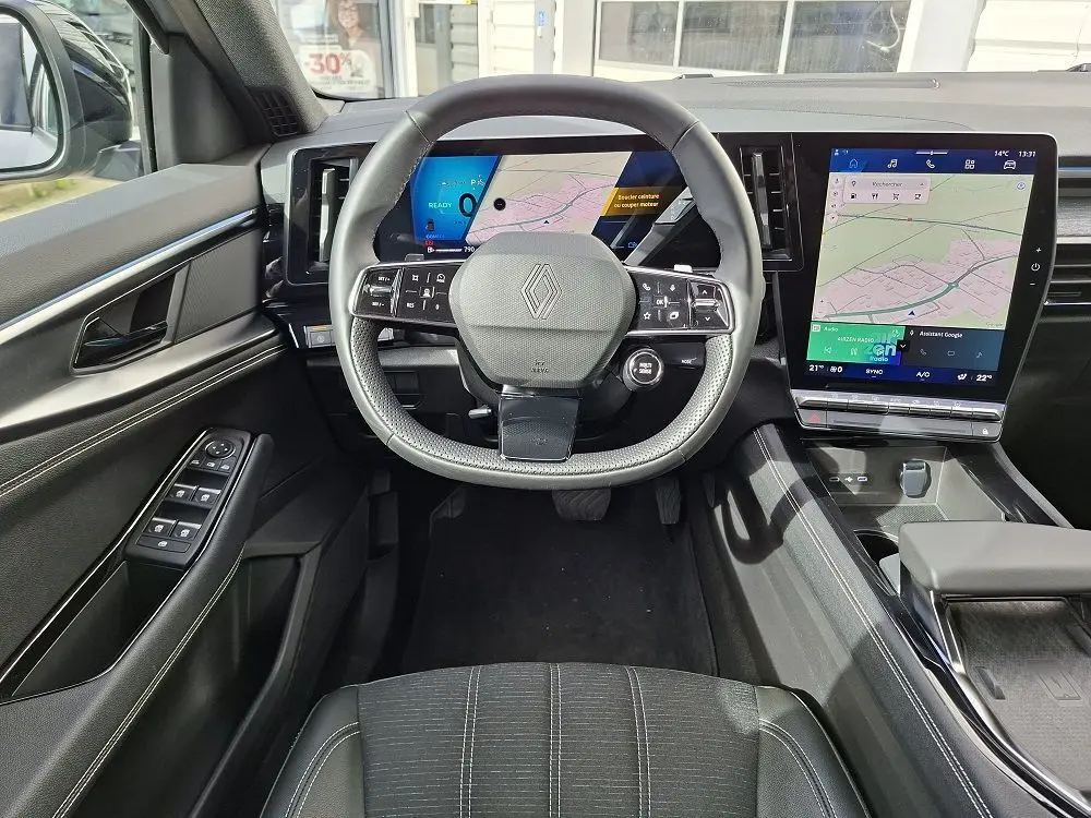 Vue intérieure centrée sur le volant de la Renault Austral gris schiste, avec tableau de bord numérique et grand écran tactile vertical.