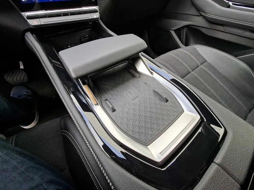 Vue intérieure rapprochée du coffre central et de la console noire brillante du Renault Austral gris schiste, avec accoudoir rembourré.