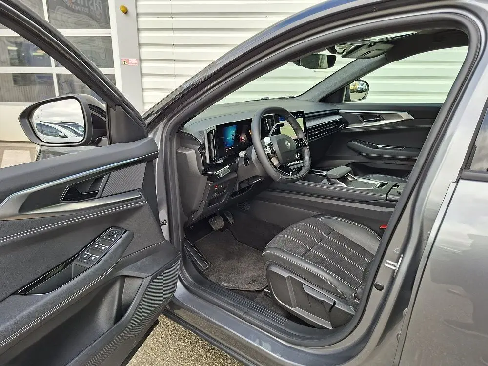 Vue intérieure côté conducteur de la Renault Austral gris schiste 2025, mettant en valeur le tableau de bord digital et les sièges en tissu.