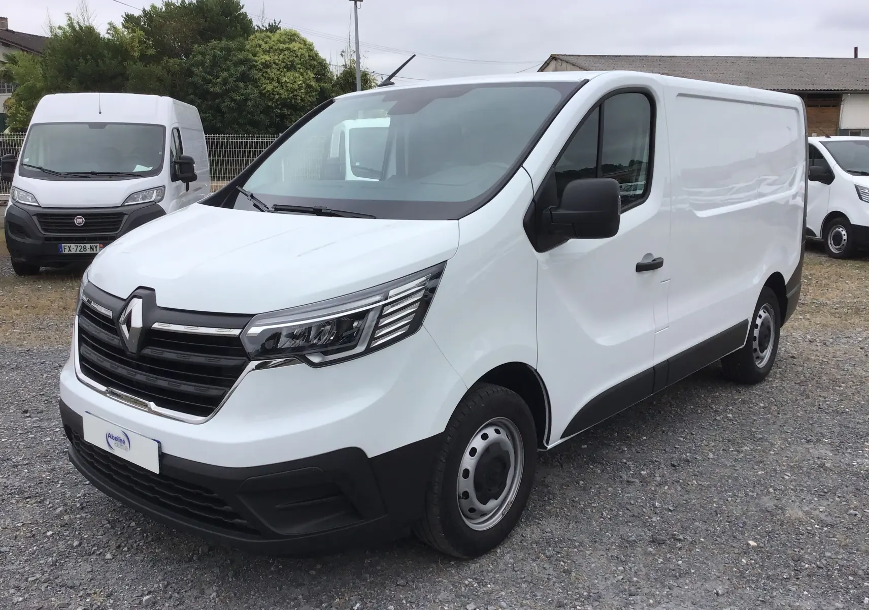 Renault Trafic Fourgon blanc vu en 3/4 avant droit, avec calandre noire et phares LED distinctifs.