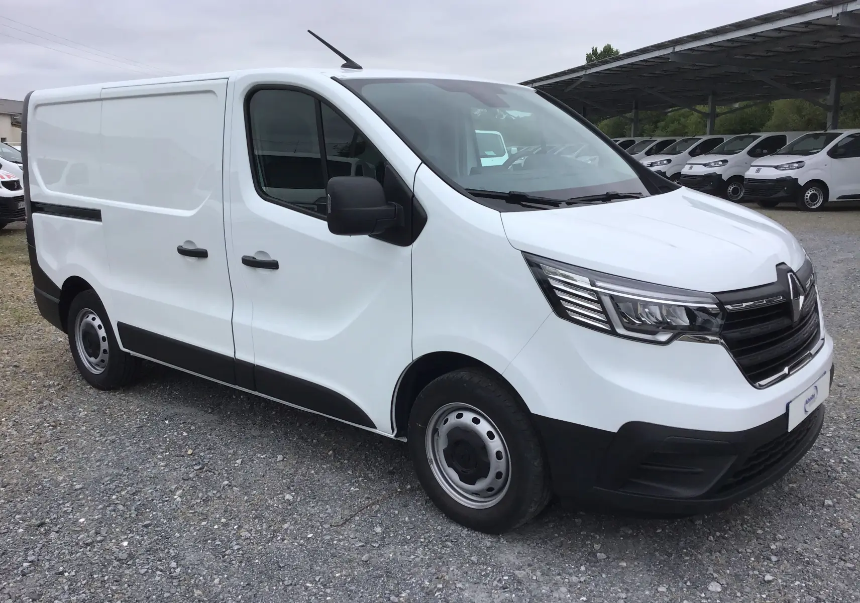 Renault Trafic Fourgon blanc en vue 3/4 avant droit, avec pare-chocs noirs et jantes acier simples.