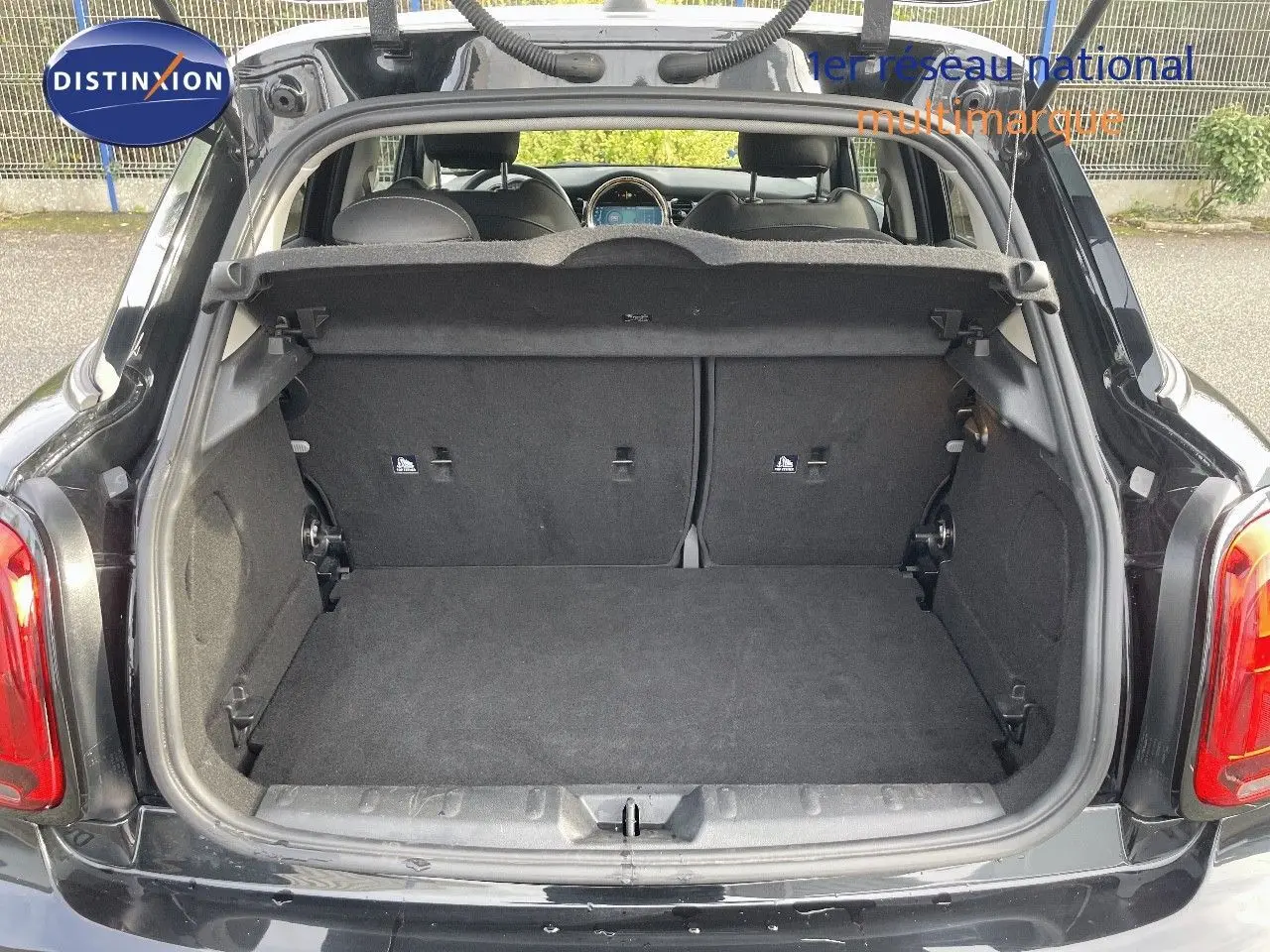 Coffre ouvert d'une MINI 1.5 136CH noir midnight metal, vue arrière montrant l'espace de chargement et l'intérieur des sièges.
