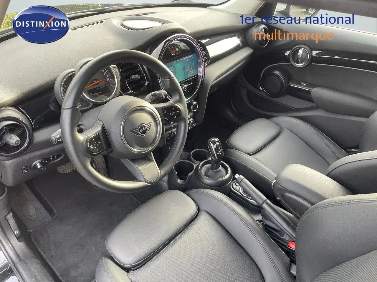 Intérieur noir cuir d'une MINI 1.5 136CH STEPTRONIC 2023, vue depuis le côté conducteur sur le tableau de bord et la console centrale.