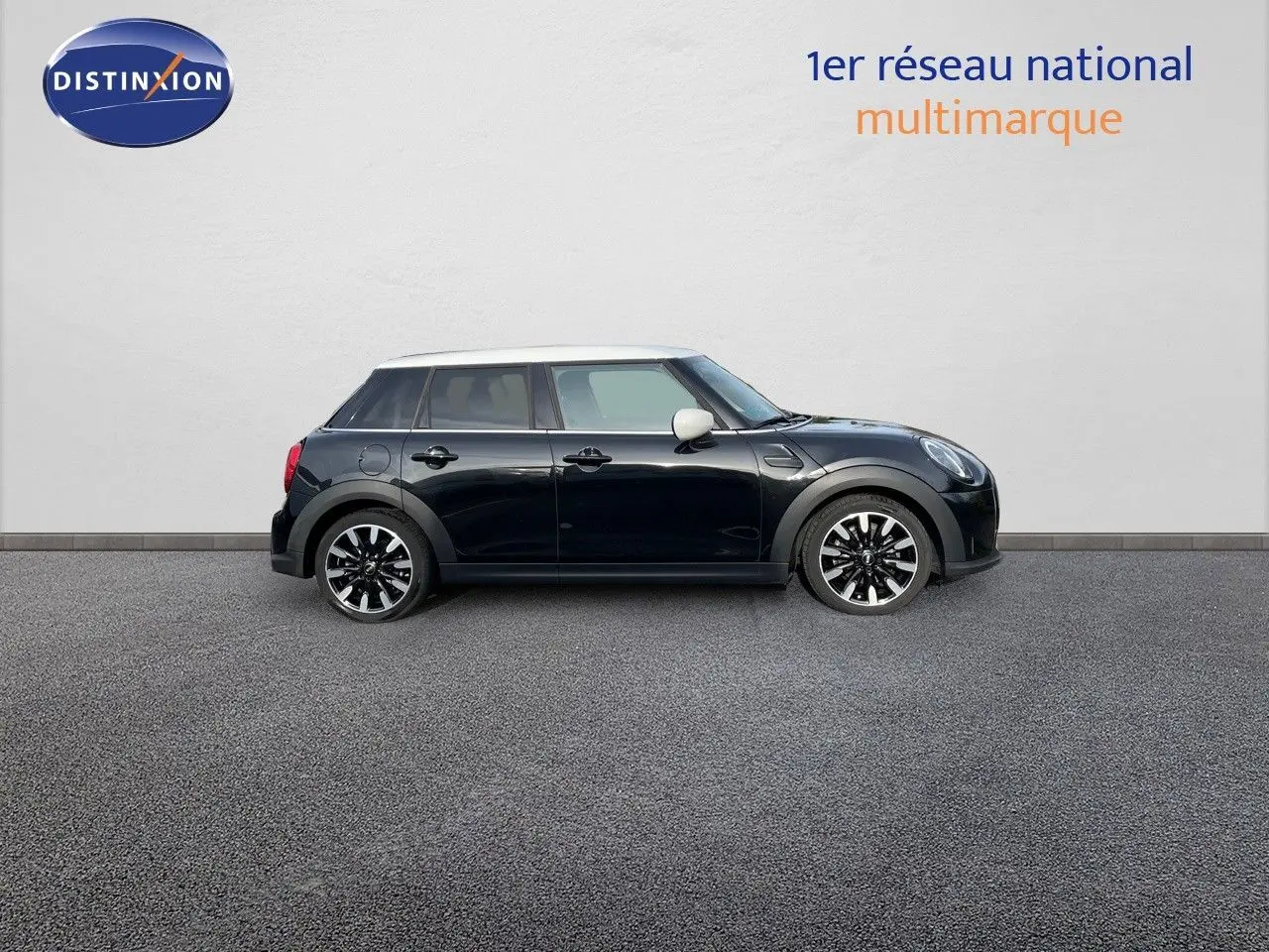 Profil droit d'une MINI 5 portes noire Midnight Metal avec toit blanc et jantes bi-ton sur fond neutre.