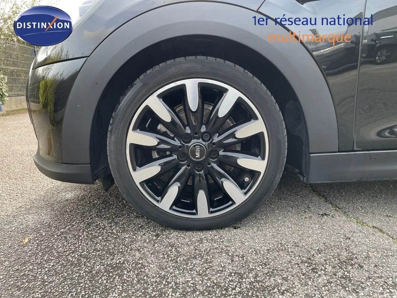 Gros plan sur la roue avant gauche noire Midnight Metal d'une MINI 1.5 136CH STEPTRONIC 2023 avec jante bi-ton.