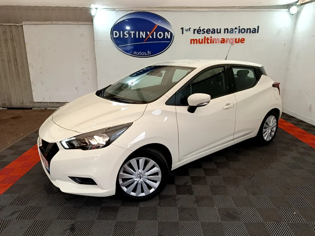 Nissan Micra blanche vue en 3/4 avant droit dans un showroom avec éclairage intérieur et logo Distinxion.