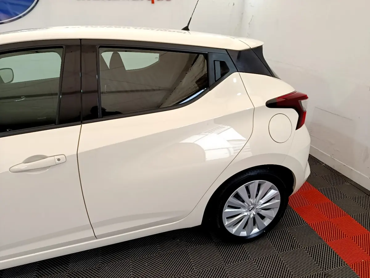 Vue côté gauche arrière d'une Nissan Micra IG-T 92 Acenta blanche avec jantes alliage et vitres teintées.
