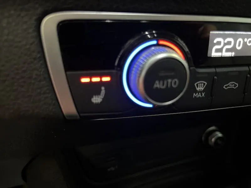 Gros plan sur le bouton de réglage automatique de la climatisation et siège chauffant activé dans l'Audi Q2 2021.