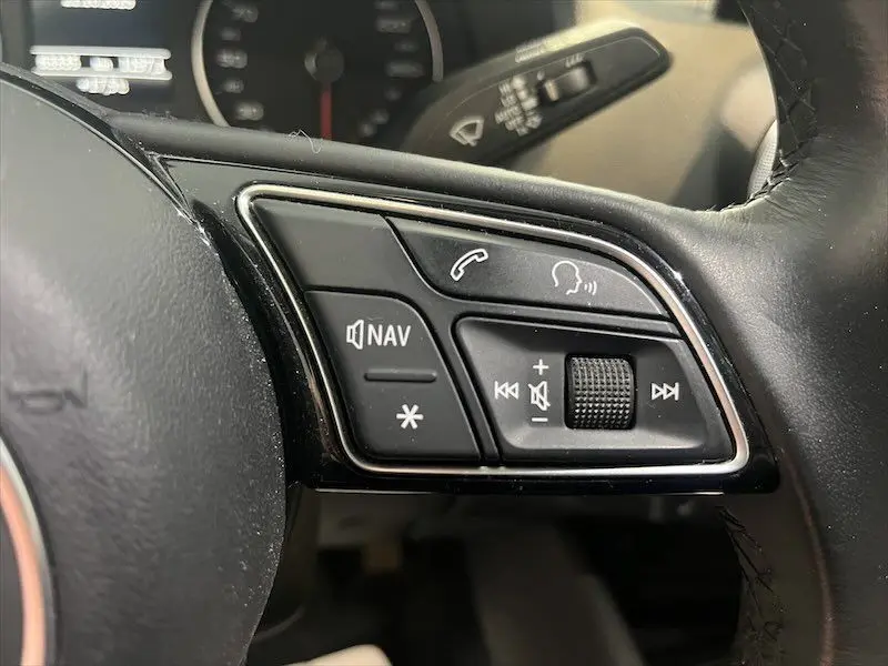 Gros plan sur les commandes du volant à droite de l'Audi Q2 30 TFSI S-Line 2021, finition noire avec boutons de navigation et audio.