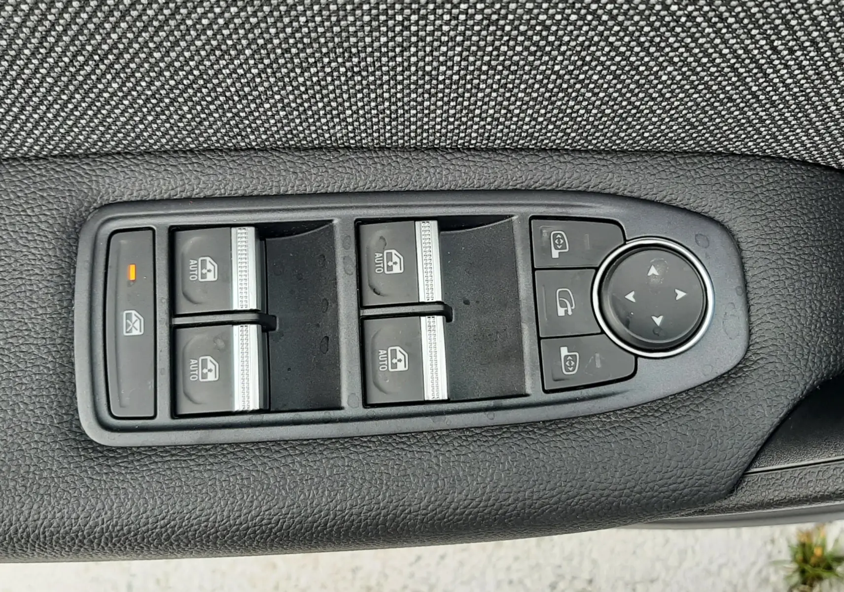 Gros plan sur les commandes de lève-vitres et rétroviseurs sur la porte intérieure noire du Renault Symbioz blanc nacré.