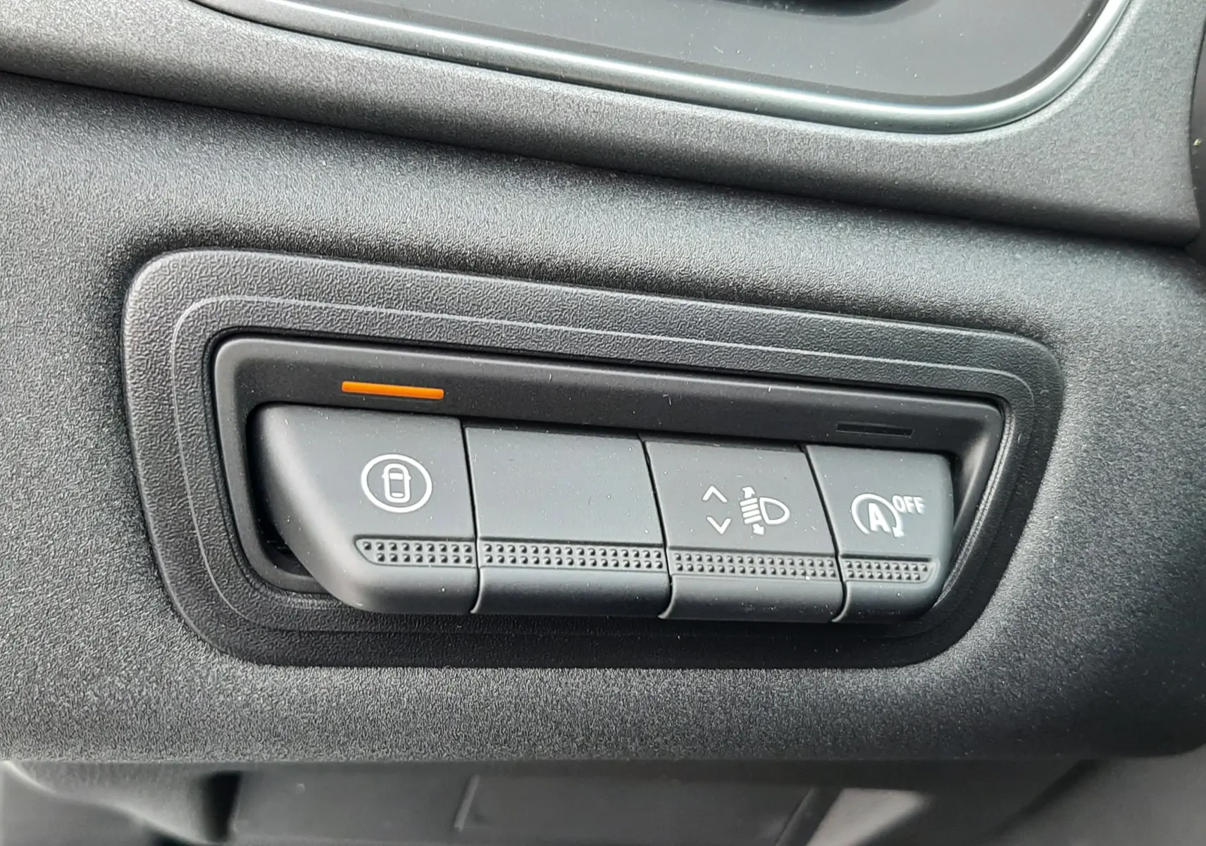 Gros plan sur les commandes noires du tableau de bord de la Renault Symbioz blanc nacré, avec témoin orange allumé.