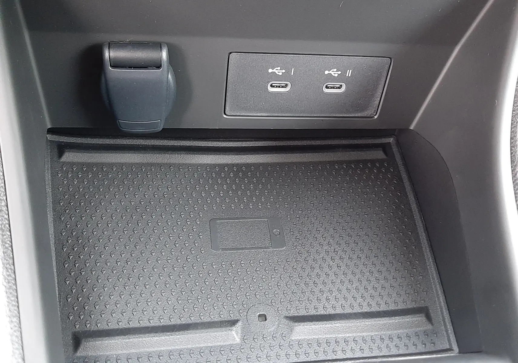 Gros plan sur la console centrale du Renault Symbioz blanc nacré, montrant deux ports USB-C et un espace de rangement antidérapant.