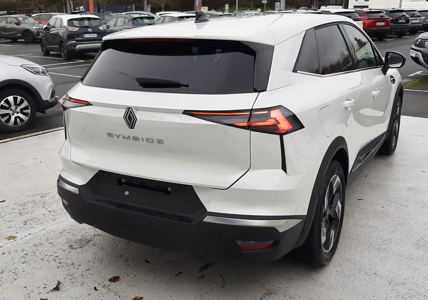 Vue 3/4 arrière droite d'une Renault Symbioz blanc nacré, avec feux arrière LED et vitres teintées.