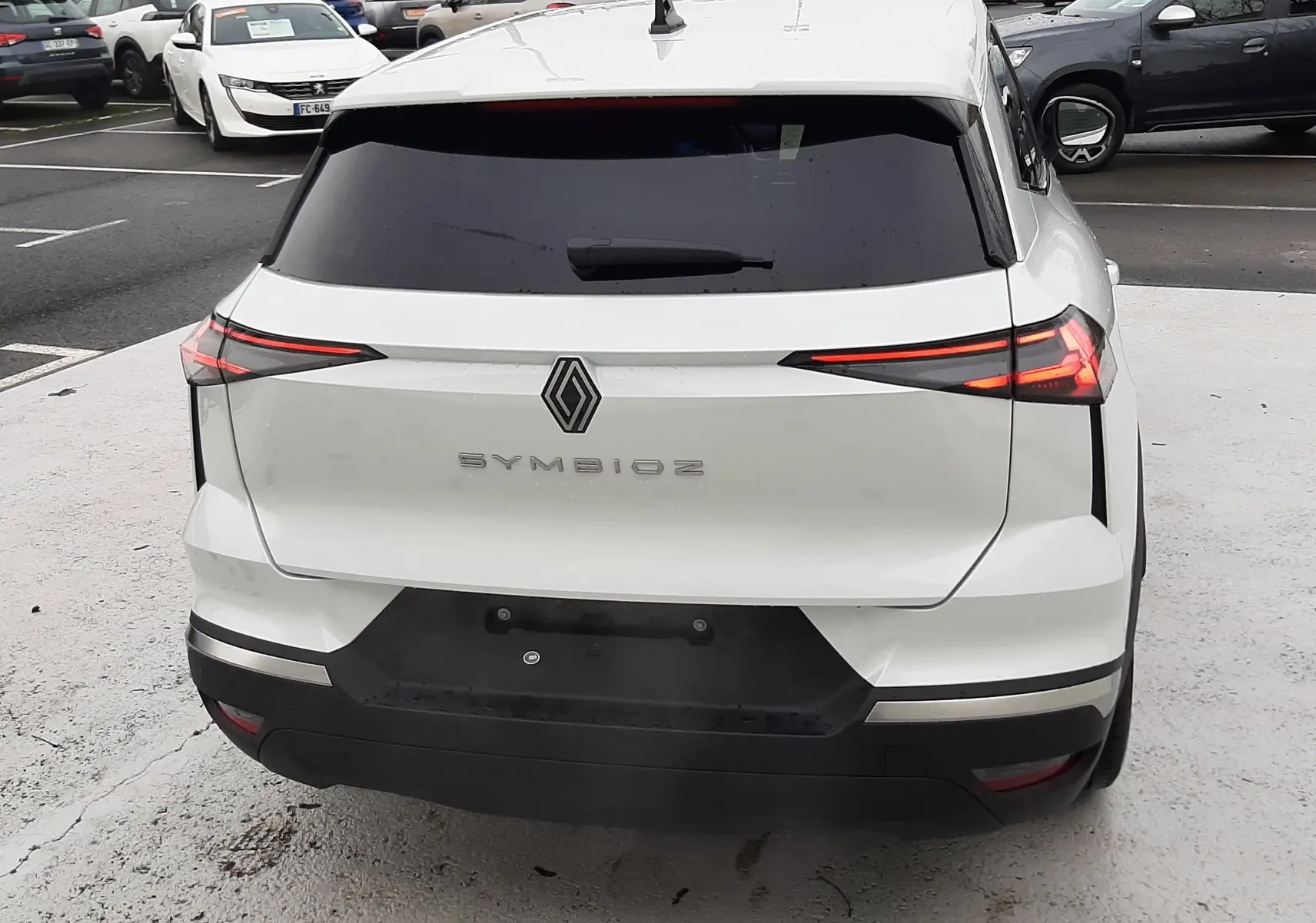 Vue arrière d'une Renault Symbioz blanc nacré avec feux arrière LED étirés et lunette arrière teintée.