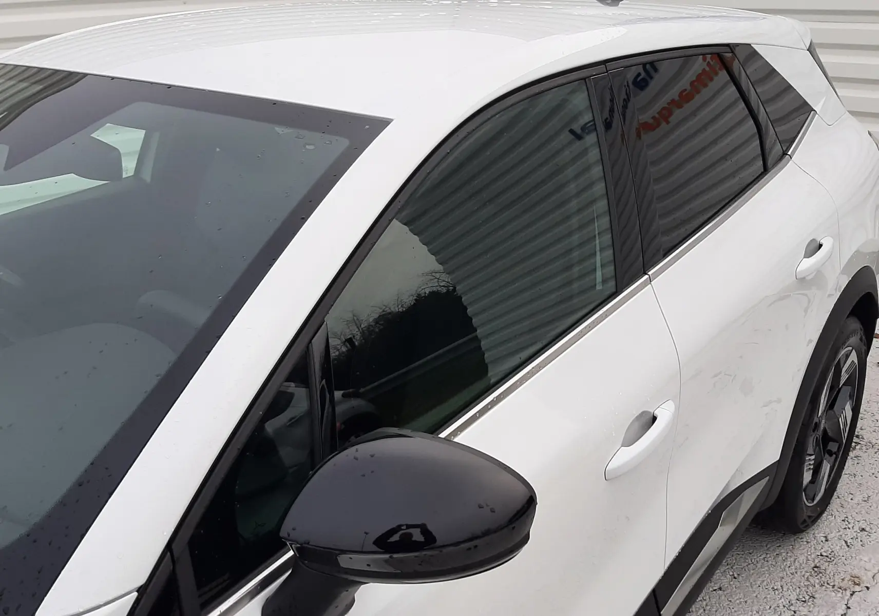 Vue 3/4 avant droit du Renault Symbioz blanc nacré, avec rétroviseur noir et vitres teintées.