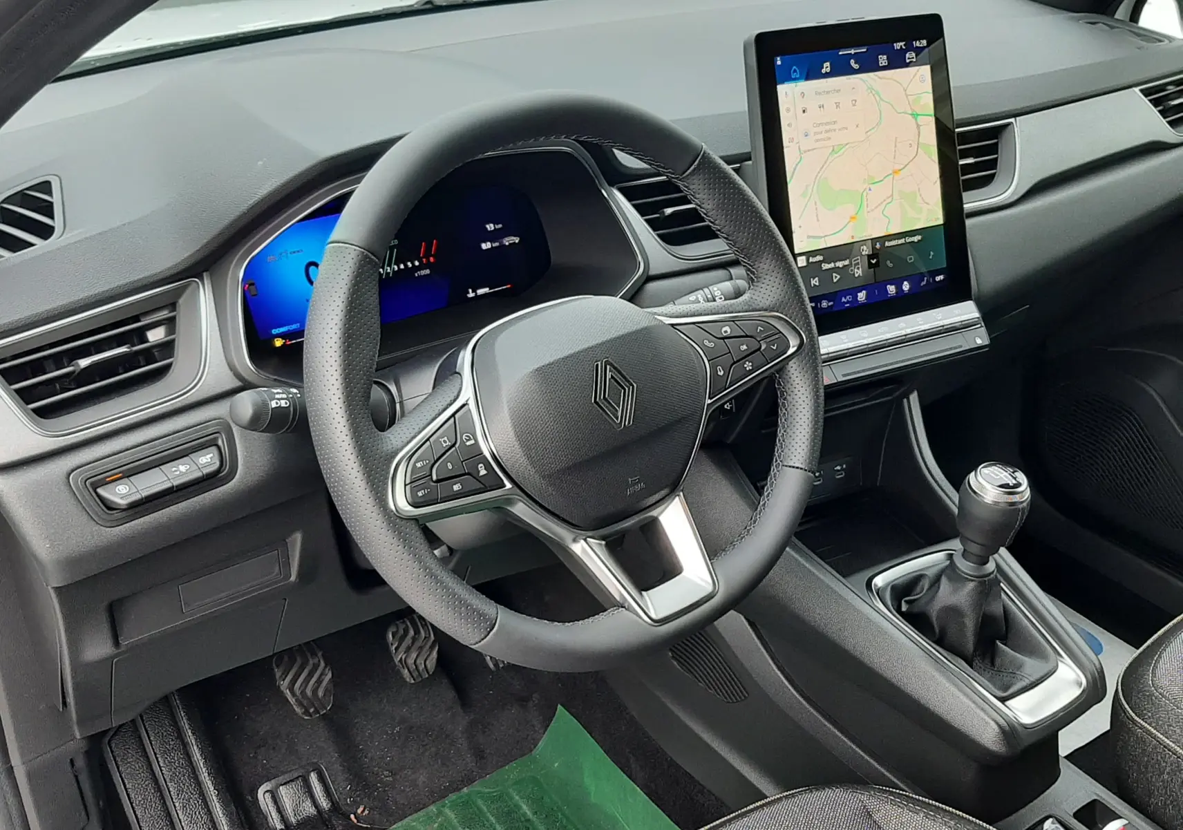Vue intérieure côté conducteur du Renault Symbioz blanc nacré 2025, volant multifonction et écran tactile vertical avec navigation.