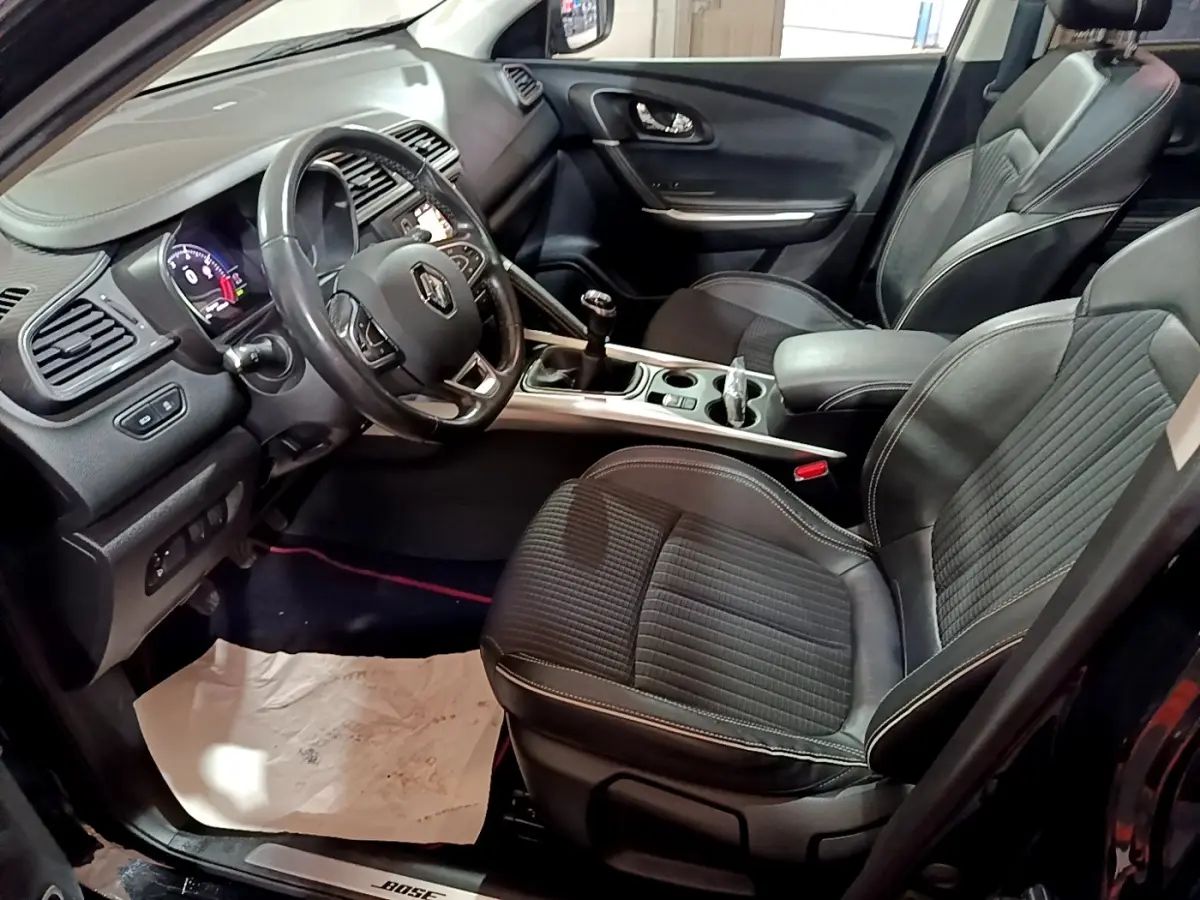 Intérieur avant du Renault Kadjar Intens noir, vue côté conducteur montrant volant cuir, sièges tissu et console centrale avec boîte manuelle.