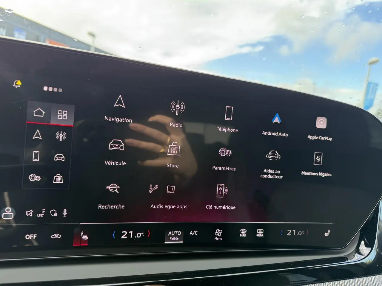 Écran tactile central de l'Audi A5 2025 affichant le menu principal avec options connectées et climatisation à 21°C.